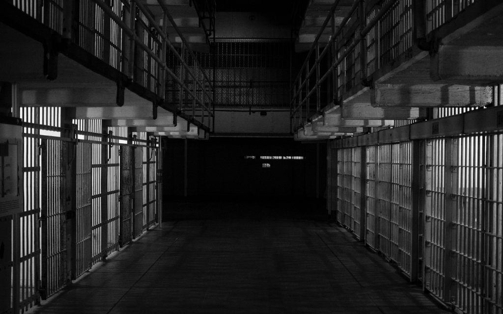 This is a black and white picture of the hall way of a jail cell which shows a series of metal caged doors, representing the bleakness of the criminal justice system as a whole and particularly in "The Night Of".