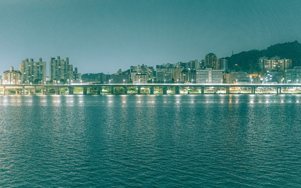 This is a look at a city in South Korea that is beautiful lit by a lake, representing luxury, similar to the opulence in " Graceful Family".