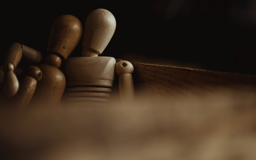 This is a brown and cream wood dolls positioned beside each other on a wooden bench. This represents the co-dependent relationship between Issa and Molly.