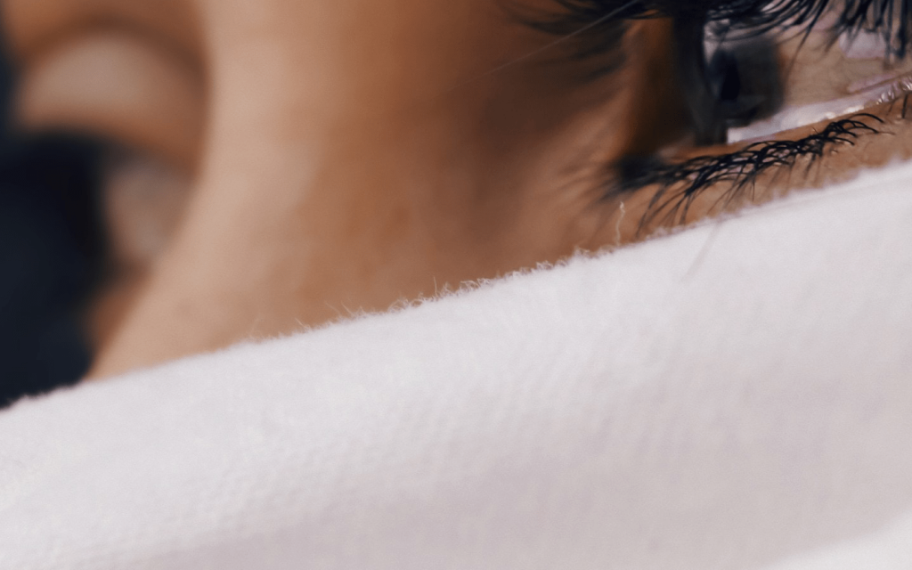 This is a close up of a White woman with tear in her eyes. The image is zoomed in to her face to just capture her eyes and her nose has been covered by a white cloth. This is used to represent the sadness in Viviane throughout the trial in "Gett".